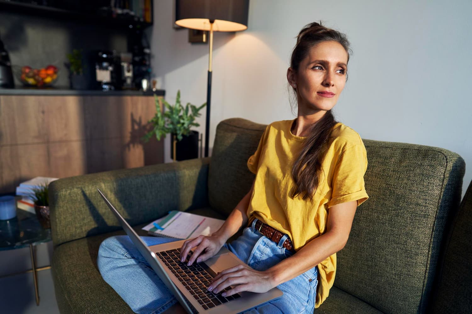 Selbstständige arbeitet mit dem Laptop entspannt auf dem Sofa