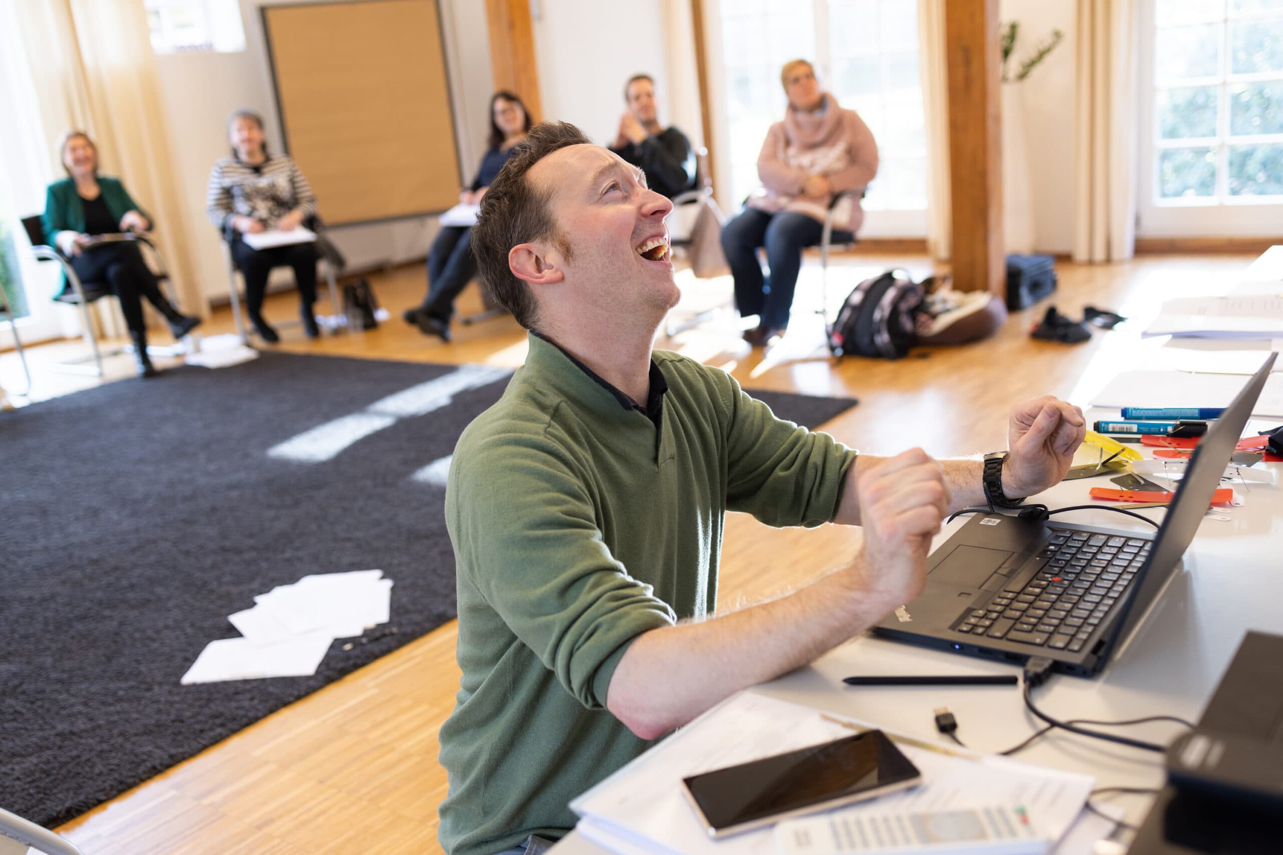 Jan Siebenmark freut sich in einem Workshop vor dem Laptop