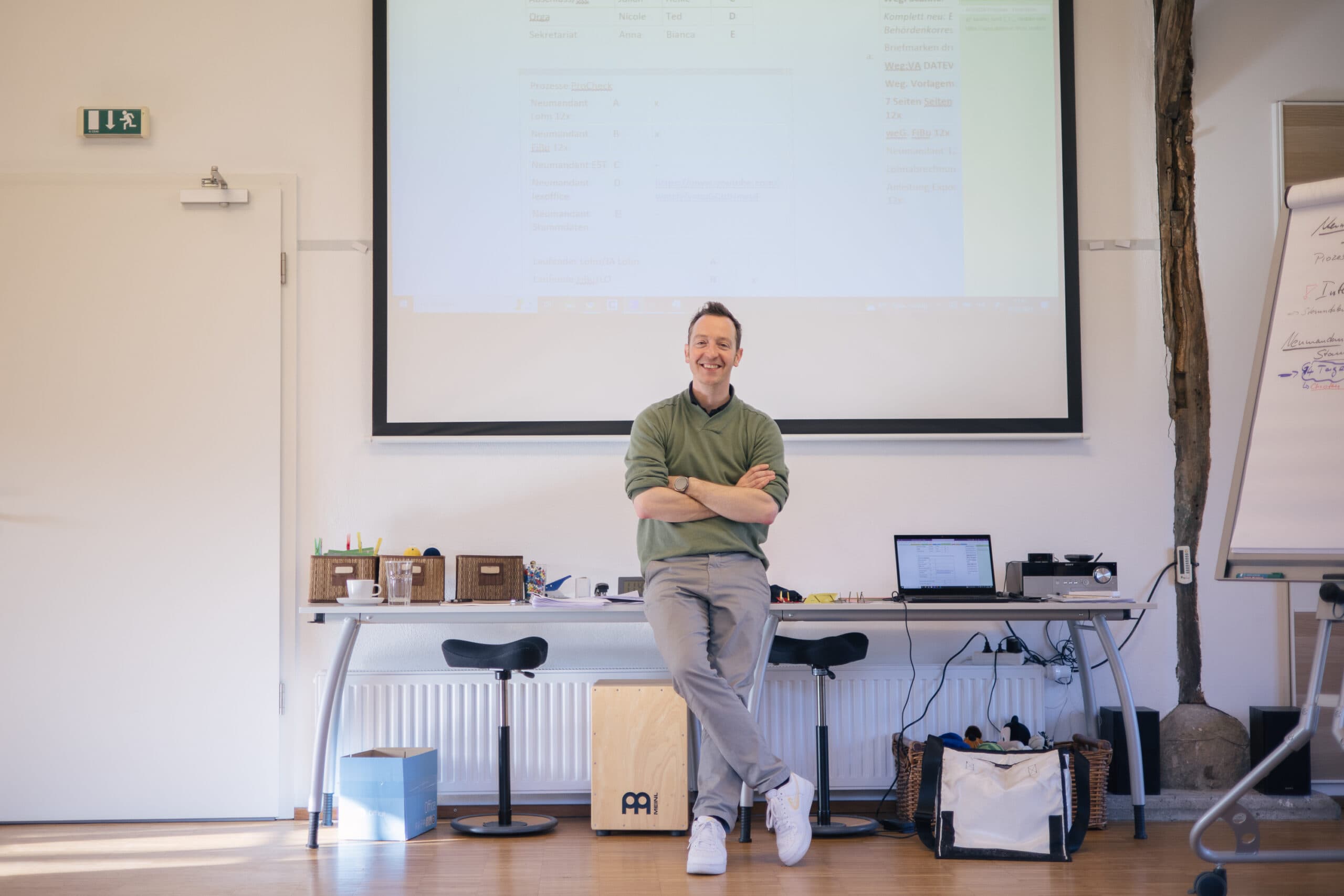 Jan Siebenmark steht lächelnd vor einer Präsentation im Workshop-Raum